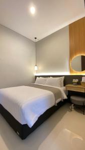 a bedroom with a large white bed and a desk at The Pinasti Villas in Tlekung