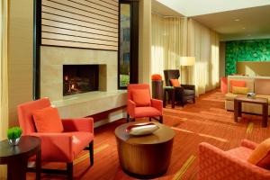 a lobby with orange chairs and a fireplace at Courtyard Birmingham Hoover in Hoover