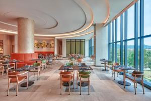 een restaurant met tafels en stoelen en grote ramen bij Courtyard by Marriott Setia Alam in Setia Alam