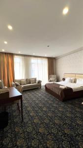 a large hotel room with two beds and a couch at Marmenio Hotel - Tbilisi in Tbilisi City