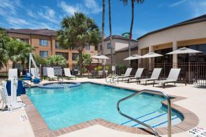 a pool at a hotel with chairs and umbrellas at Courtyard Harlingen in Harlingen