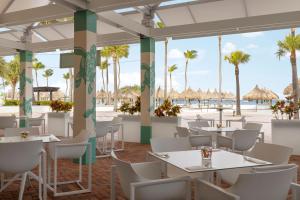 um restaurante com mesas e cadeiras brancas e palmeiras em Marriott's Aruba Ocean Club em Palm-Eagle Beach