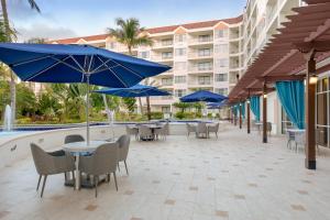 un patio con mesas y sillas y sombrillas azules en Marriott's Aruba Ocean Club, en Palm-Eagle Beach