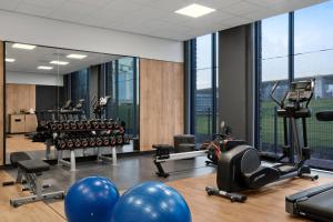 a gym with exercise equipment and large windows at Renaissance Amsterdam Schiphol Airport Hotel in Aalsmeer