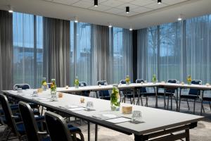 Renaissance Amsterdam Schiphol Airport Hotel في سخيبول: قاعة اجتماعات مع طاولات وكراسي ونوافذ كبيرة