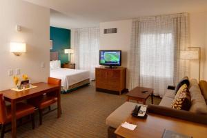 Habitación de hotel con sofá, cama y TV en Residence Inn by Marriott Wichita East At Plazzio en Wichita