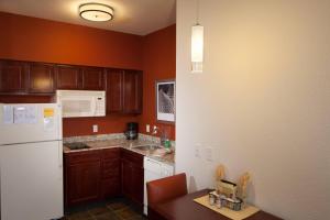 a kitchen with wooden cabinets and a white refrigerator at Residence Inn by Marriott Wichita East At Plazzio in Wichita