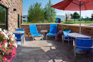a patio with blue chairs and tables and an umbrella at TownePlace Suites by Marriott Saginaw in Saginaw