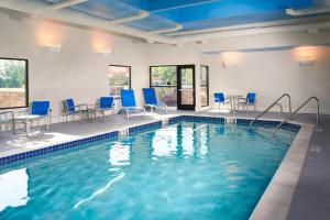 a swimming pool with blue chairs and tables in a building at TownePlace Suites by Marriott Saginaw in Saginaw