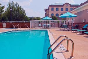 a swimming pool with chairs and umbrellas next to a building at Residence Inn by Marriott Lake Norman in Huntersville