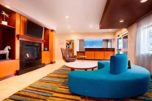 a living room with a blue chair and a table and a fireplace at Sonesta Essential Houston Energy Corridor in Houston