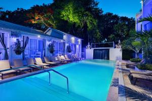 una piscina con tumbonas alrededor por la noche en The Saint Hotel Key West, Autograph Collection en Cayo Hueso