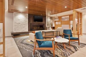 sala de estar con mesa, sillas y chimenea en Fairfield Inn & Suites by Marriott Kalamazoo en Kalamazoo