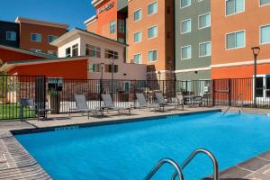 - une piscine dans une cour avec des chaises et des bâtiments dans l'établissement Residence Inn by Marriott Lubbock Southwest, à Lubbock