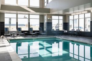 uma piscina num hotel com cadeiras, mesas e janelas em Residence Inn by Marriott Wilkes-Barre Arena em Wilkes-Barre