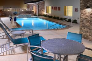 ヒューストンにあるTownePlace Suites by Marriott Houston Galleria Areaのプールの前にテーブルと椅子が備わるプールを提供しています。