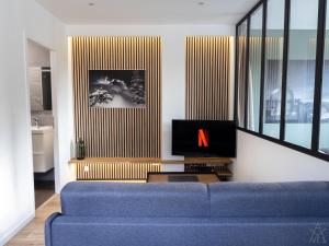 een woonkamer met een blauwe bank en een tv bij Appartement - Le Petit Loft - in Tarbes