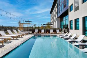 una piscina con tumbonas y un edificio en AC Hotel by Marriott Austin Hill Country, en Austin