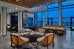 a lobby with chairs and tables and large windows at AC Hotel by Marriott Austin Hill Country in Austin