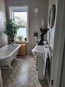 a bathroom with a tub and a sink and a bath tub at Ocean Retreat Norfolk in Trimingham