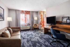 Cette chambre d'hôtel dispose d'un canapé et d'un bureau avec une télévision. dans l'établissement Fairfield Inn & Suites by Marriott Salt Lake City Downtown, à Salt Lake City