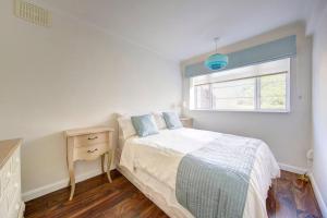 a bedroom with a bed and a dresser and a window at 2 bed flat - SW London with parking in Teddington