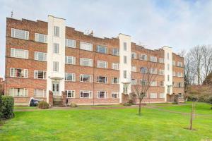 a large brick building with a green lawn in front of it at 2 bed flat - SW London with parking in Teddington +7 photos