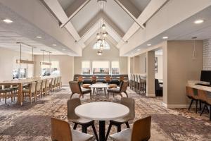 a waiting room with tables and chairs and a bar at Residence Inn Deptford in Almonesson