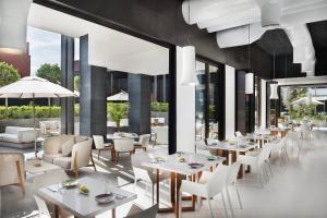 a restaurant with white tables and chairs and large windows at La Ville Hotel & Suites CITY WALK Dubai, Autograph Collection in Dubai