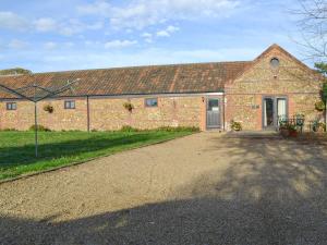 a brick barn with a driveway in front of it at Littlewood Barn - Ukc3737 in Bawdeswell