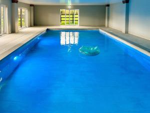 a large swimming pool with blue water at Littlewood Barn - Ukc3737 in Bawdeswell