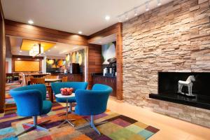 a lobby with blue chairs and a fireplace at Fairfield Inn & Suites Lansing West in Delta Center Township