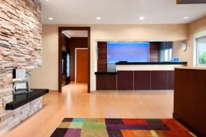 a lobby with a tv and a stone wall at Fairfield Inn & Suites Lansing West in Delta Center Township
