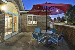 a table with chairs and an umbrella on a patio at TownePlace Suites Detroit Dearborn in Dearborn