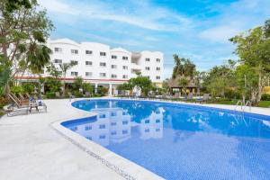 uma piscina de resort com um hotel ao fundo em Courtyard by Marriott Cancun Airport em Cancún