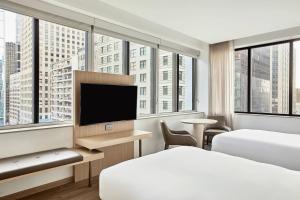 ヒューストンにあるAC Hotel by Marriott Houston Downtownのベッド2台、薄型テレビが備わるホテルルームです。