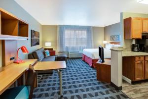 リボニアにあるTownePlace Suites by Marriott Detroit Livoniaのベッドとリビングルームが備わるホテルルームです。