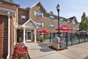 a building with a fence and a street light and flowers at TownePlace Suites by Marriott Detroit Livonia in Livonia