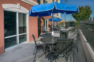 a table and chairs with a blue umbrella on a patio at Fairfield Inn & Suites by Marriott Dover in Dover