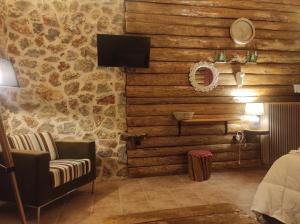 a room with a couch and a tv and a wall of stones at Ο Σκίουρος Παραδοσιακοί Ξενώνες in Oíti