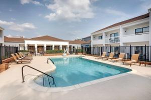 una piscina con sillas y un edificio en Courtyard Dallas Addison Midway, en Addison