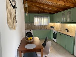 a kitchen with green cabinets and a table with a bowl of fruit at JAVA GEVA zen living in Kalamaki