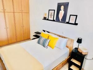 a bedroom with a bed with yellow and white pillows at JAVA GEVA zen living in Kalamaki