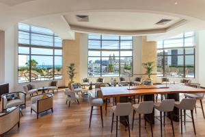 a restaurant with tables and chairs and large windows at Malta Marriott Resort & Spa in St. Julianʼs