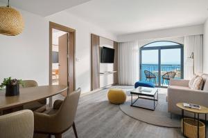 a living room with a table and a room with a view at Malta Marriott Resort & Spa in St. Julianʼs