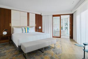 a bedroom with a bed with a bench in it at Malta Marriott Resort & Spa in St. Julianʼs