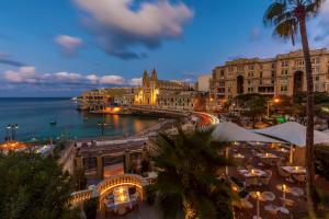 a view of a city at night with the ocean at Malta Marriott Resort & Spa in St. Julianʼs