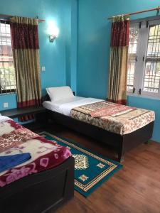 Duas camas num quarto com paredes e janelas azuis em GAUTAM GARDEN GUEST HOUSE em Pokhara