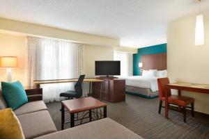 コーパスクリスティにあるResidence Inn Corpus Christiのベッドとリビングルームが備わるホテルルームです。