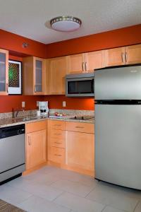 a kitchen with wooden cabinets and a white refrigerator at MainStay Suites Appleton Airport - Fox River Mall Area in Appleton